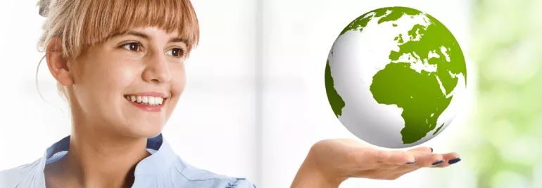 Woman holding a globe in one hand and smiling at it