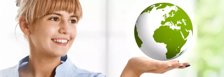 Woman holding a globe in one hand and smiling at it