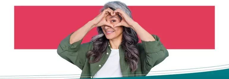 Person making a heart shape with hands and smiling.