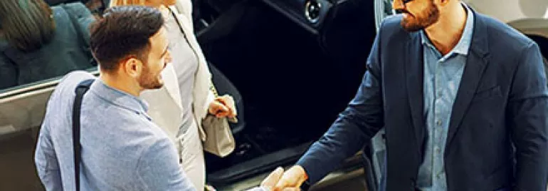 People shaking hands in a car dealership.