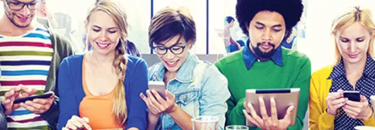 Un groupe de personnes autour d'une table utilisant des téléphones et tablettes.