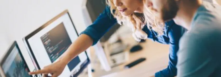 Deux personnes collaborant à un bureau informatique.