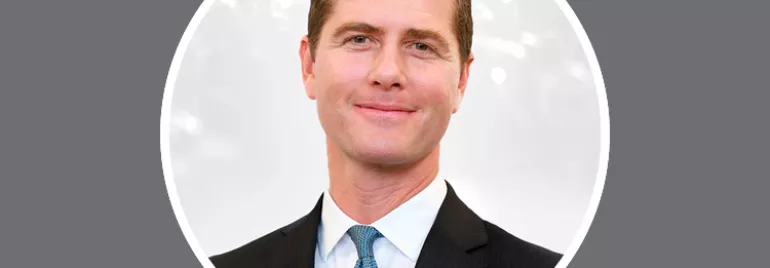 Personne en costume souriant avec un fond blanc.
