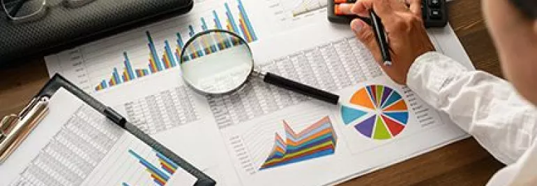 Personne analysant des graphiques financiers avec une calculatrice.