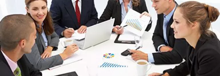 Groep professionals in vergadering, bespreken grafieken aan tafel.