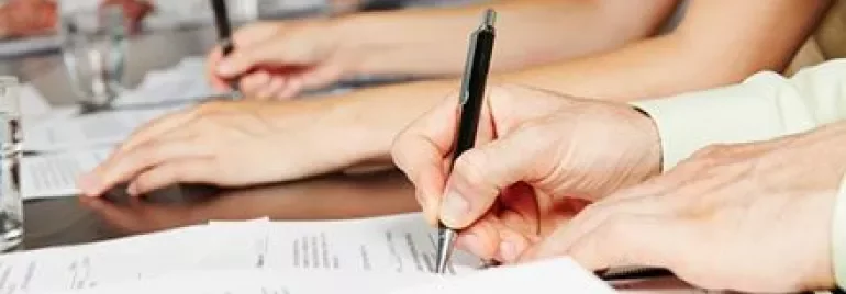 Group of people writing on documents at a table.
