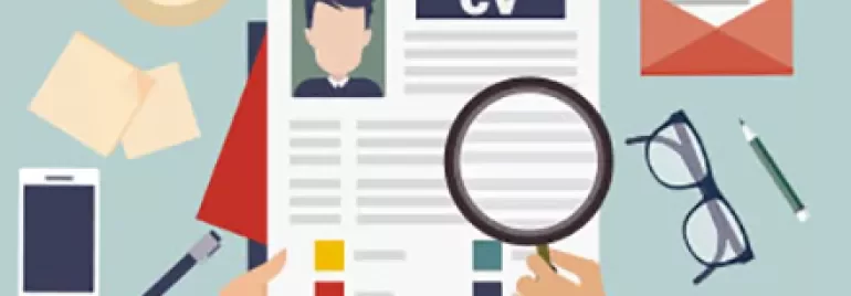 Person reviewing CV with magnifying glass on cluttered desk.