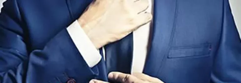 Person adjusting a blue suit and tie.