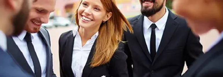 Groupe de collègues en tenue professionnelle discutant à l'extérieur.