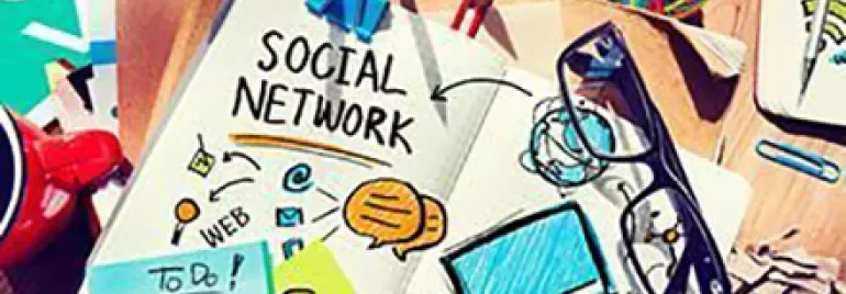 Desk with notebook titled 'Social Network' surrounded by notes and office supplies.