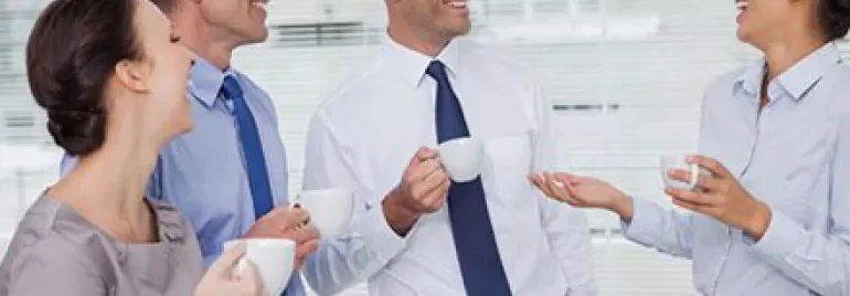 Groupe de personnes en tenue de bureau discutant en buvant du café.