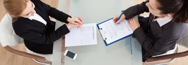 Two people sitting at a table, reviewing documents.