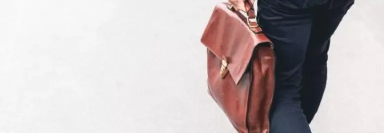 Personne marchant avec une mallette en cuir marron.