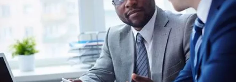 Deux personnes en réunion d'affaires avec un ordinateur portable et une tablette.