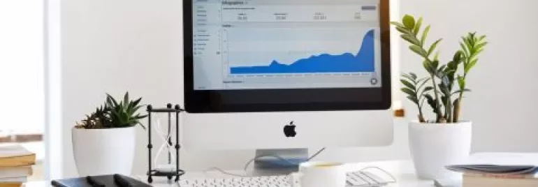 Ordinateur sur un bureau avec graphique à l'écran et plantes à côté.