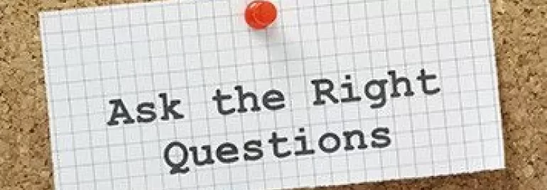 Notecard pinned on corkboard with 'Ask the Right Questions' written on it.