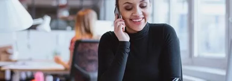 Persoon aan de telefoon glimlacht op kantoor.