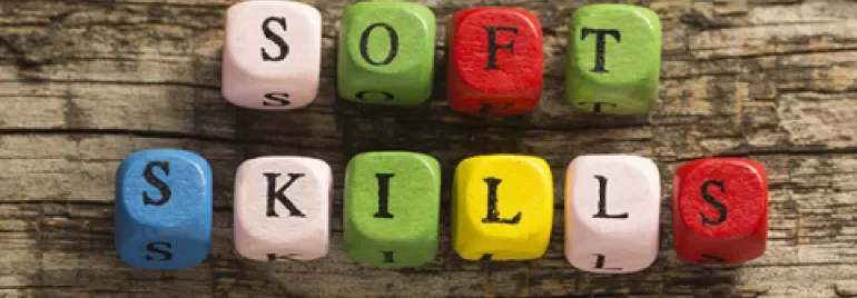 Cubes de lettres colorées épelant 'soft skills' sur fond de bois.