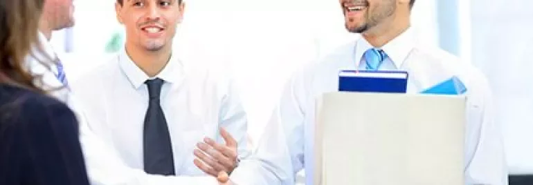 Office workers shaking hands, one holding a box.