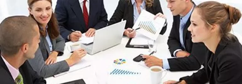 Groupe de personnes en réunion avec graphiques et ordinateurs.