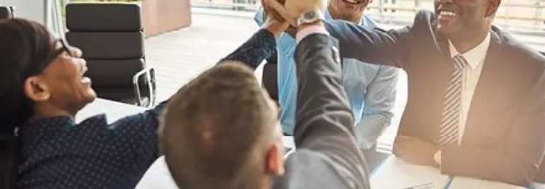 Business team celebrating with a high five at a meeting.