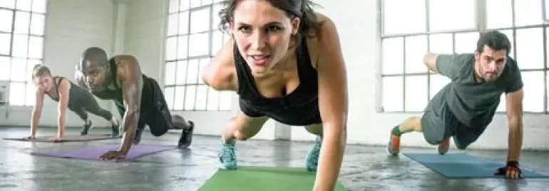 Groupe faisant de l'exercice à l'intérieur, en position de planche sur des tapis de yoga.