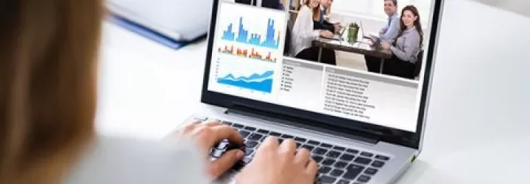 Persoon gebruikt laptop voor videoconferentie met grafieken en vergadering.
