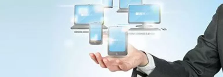 Hand holding digital devices with glowing screens.
