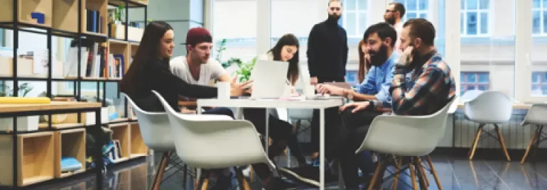 Groupe de collègues collaborant autour d'une table dans un bureau moderne.