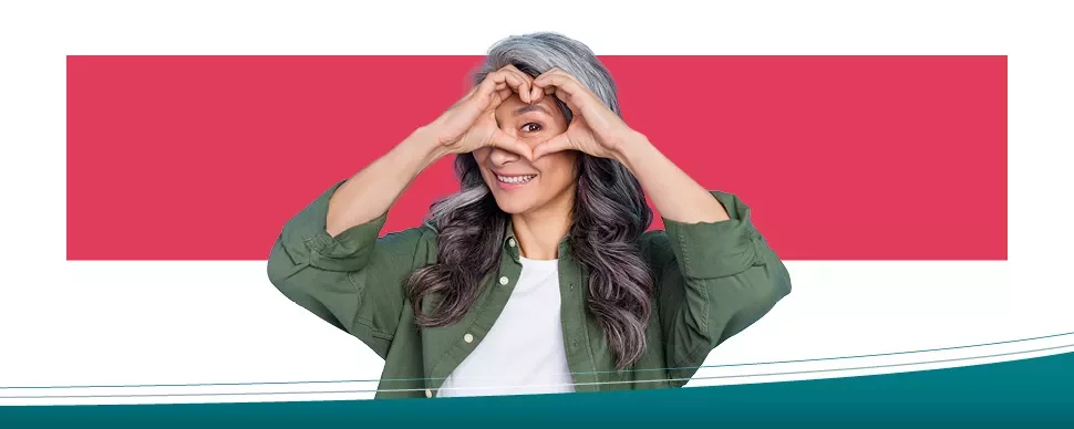 Person making a heart shape with hands and smiling.