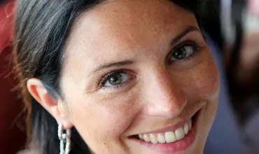Person smiling at the camera with sparkling earrings.