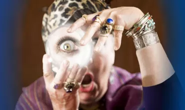 Personne tenant une boule de cristal avec une expression surprise et des bijoux