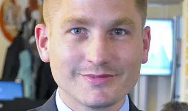 Persoon in pak lacht binnenshuis.