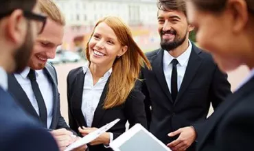 Un groupe de personnes en tenue professionnelle souriant et discutant.