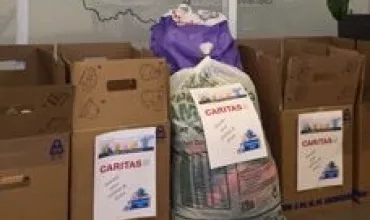 Boxes and bags labeled 'CARITAS' ready for donation.