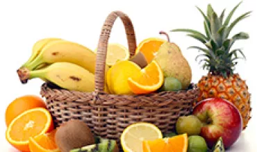 Un panier avec divers fruits comme des bananes, des oranges et un ananas.