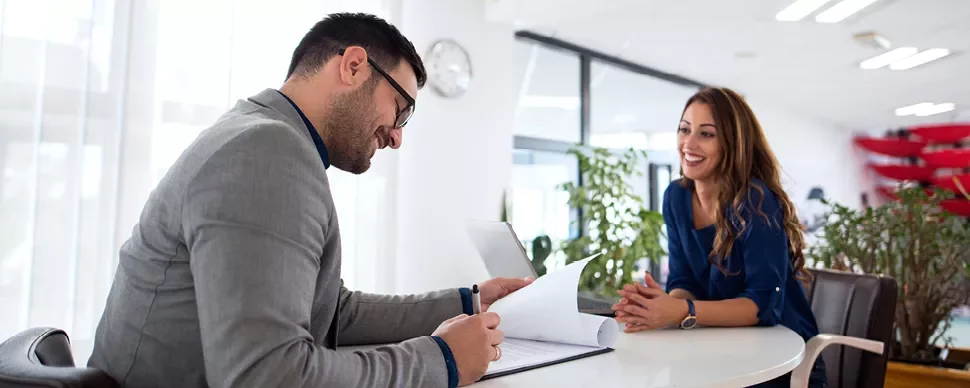 Two people having a conversation at a table in an office.