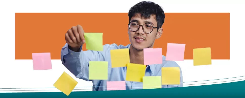 Person arranging colorful sticky notes on a glass surface.