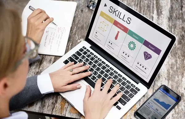 Person working on skills assessment on a laptop at a wooden table.