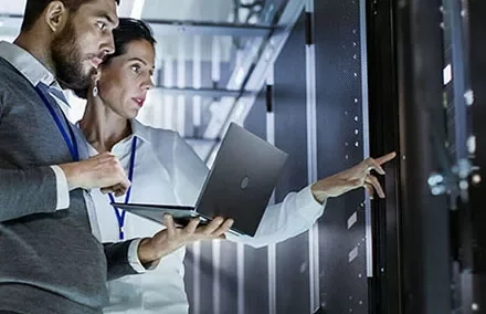 Two people analyzing server data with a laptop.