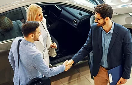 Mensen schudden handen in een autodealer.