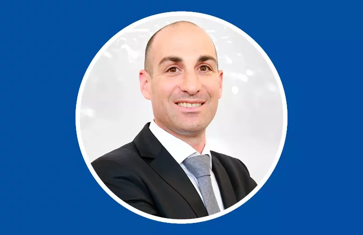 Person in suit smiling against blue background