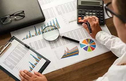 Persoon die financiële grafieken met een rekenmachine analyseert.