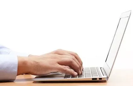 Mains tapant sur un clavier d'ordinateur portable.