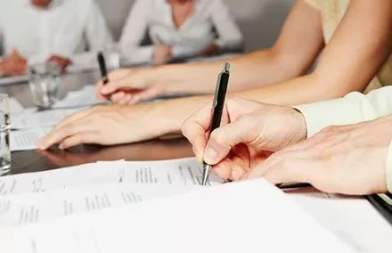 Group of people writing on documents at a table.