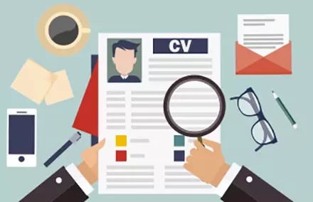 Person reviewing CV with magnifying glass on cluttered desk.