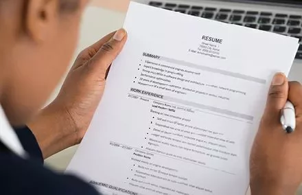Person holding a resume while writing notes.