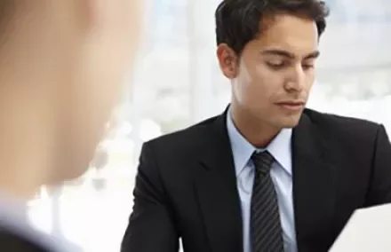 Person in a suit reviewing documents in an office setting.