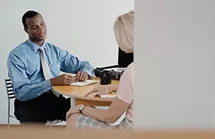 Two people having a conversation at a small table in an office setting.