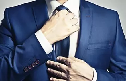 Person adjusting a blue suit and tie.